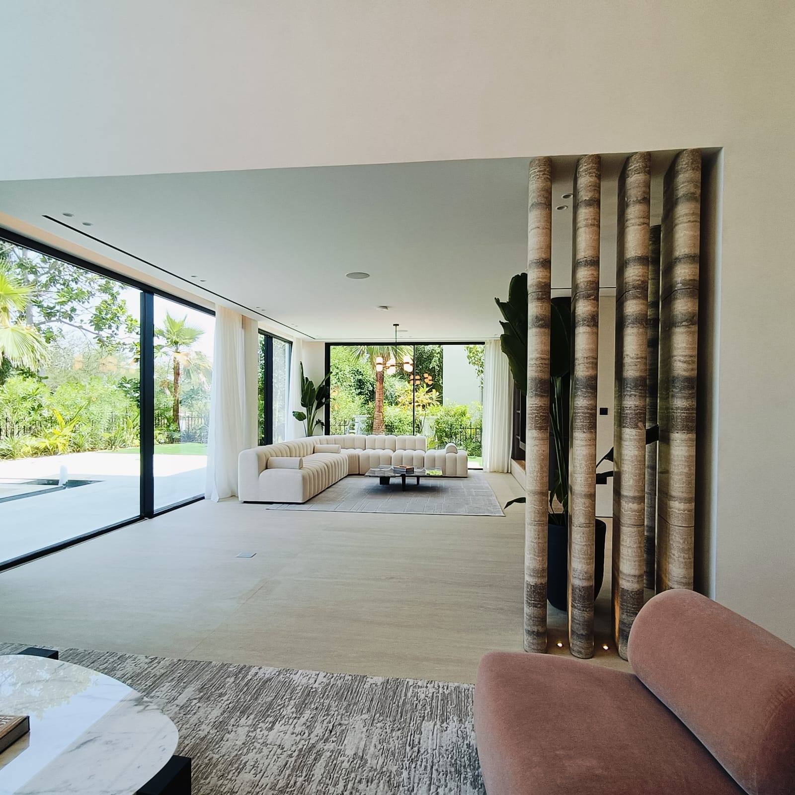 Open-plan living space with full-height glazing and sheer curtains